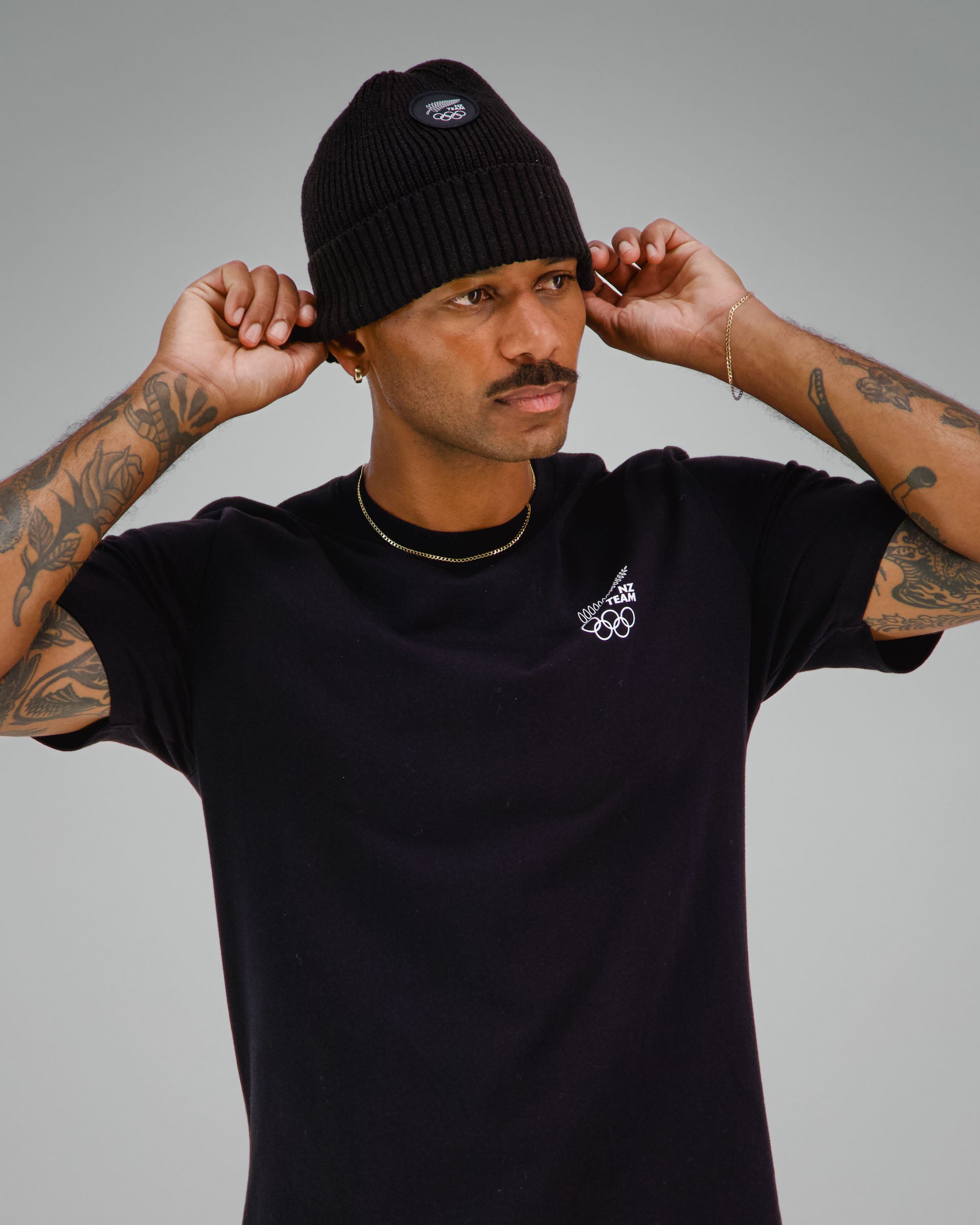 Man wearing a black t-shirt with NZ Team logo on front left side
