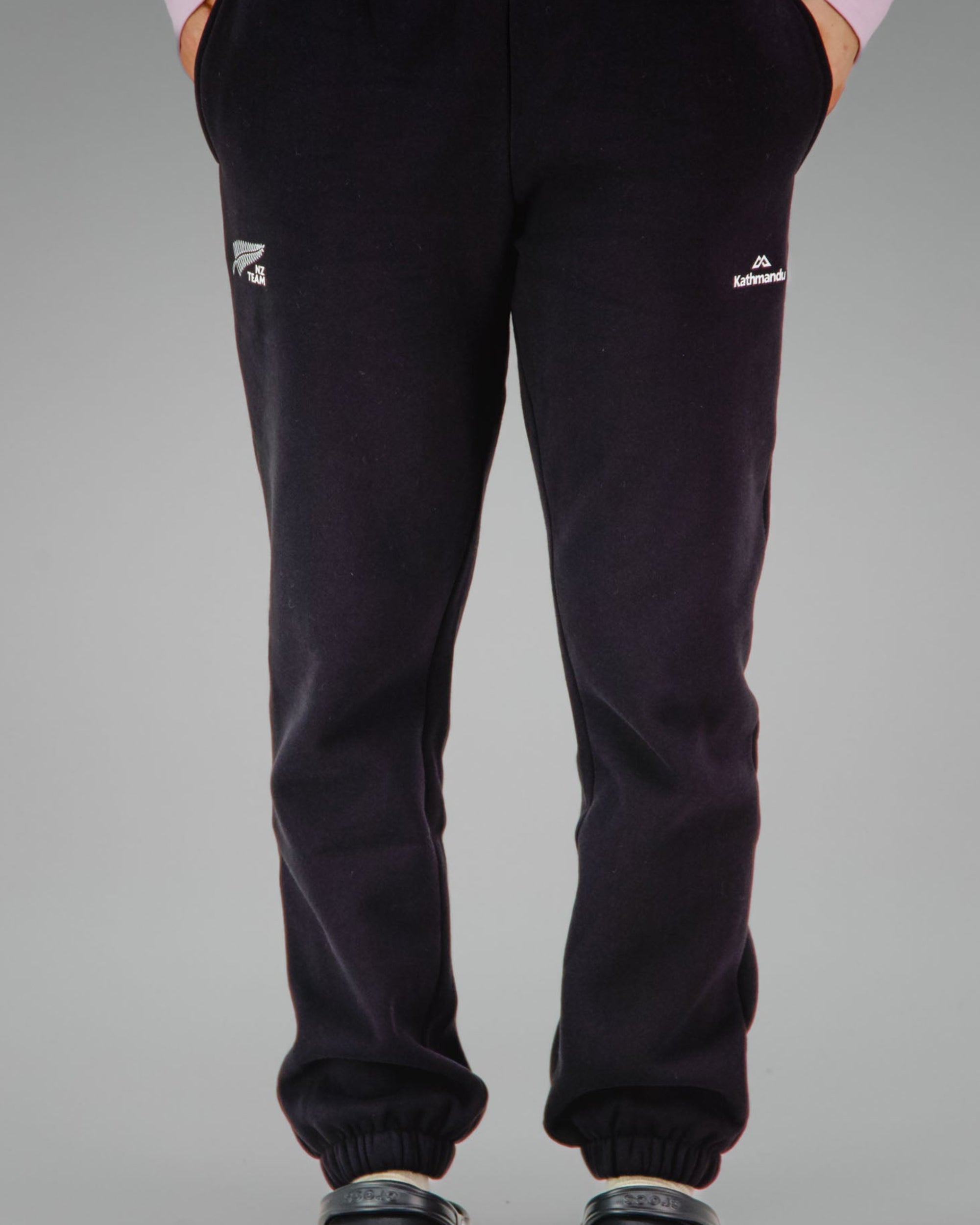Person wearing black sweatpants with NZ team logo on the right front pocket
