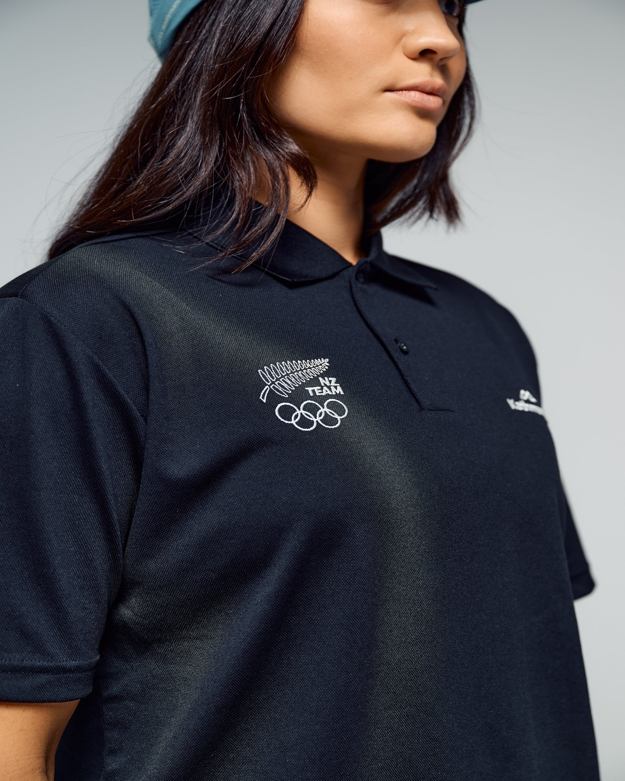 Person wearing a black polo shirt with NZ team logo
