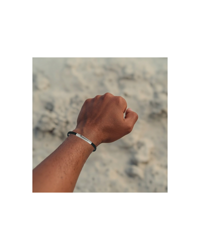Black woven bracelet on wrist of person over sandy background