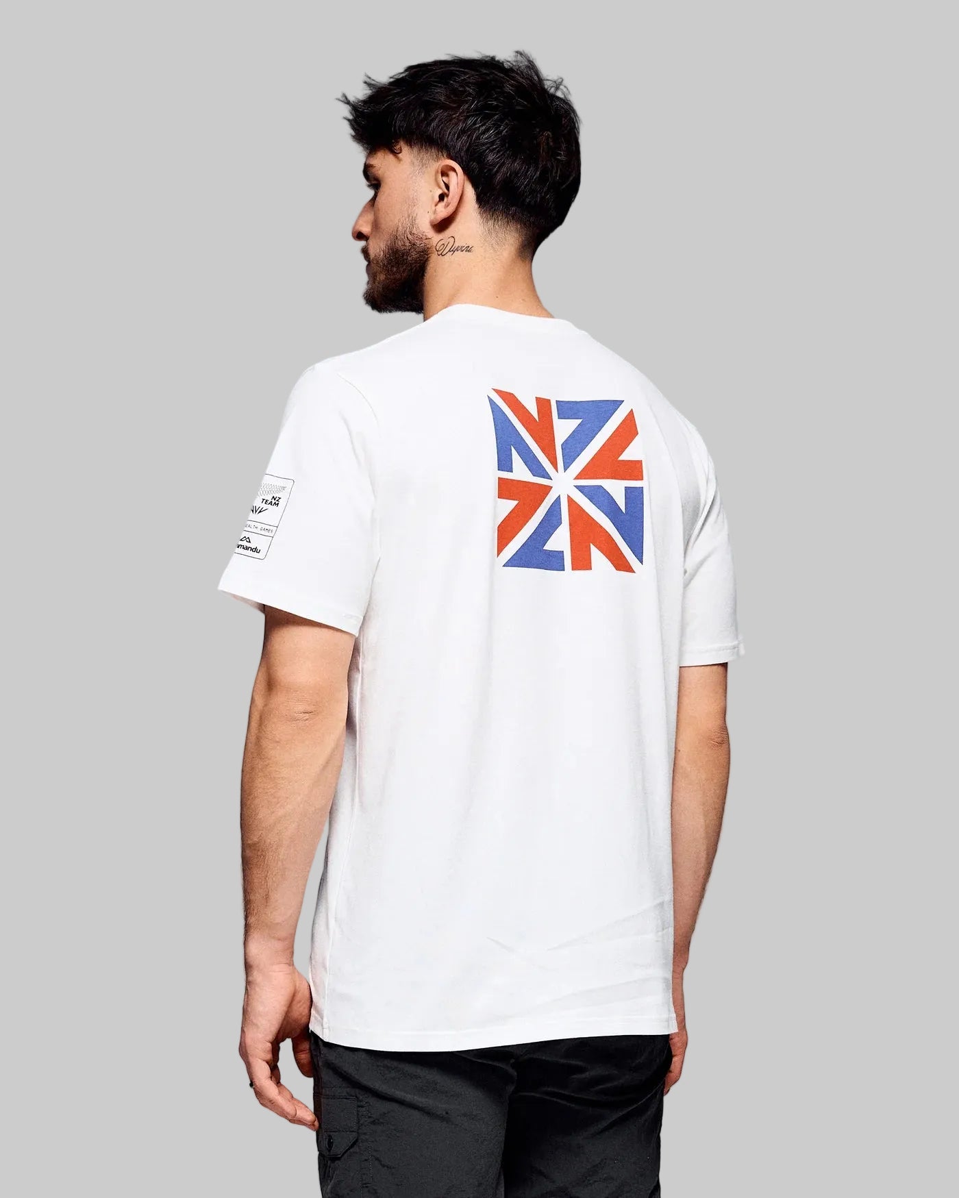 Man wearing a white t-shirt with a Union Jack design on the back against a gray background