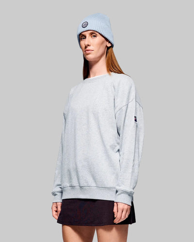 Person wearing a light gray sweatshirt and blue beanie on a gray background