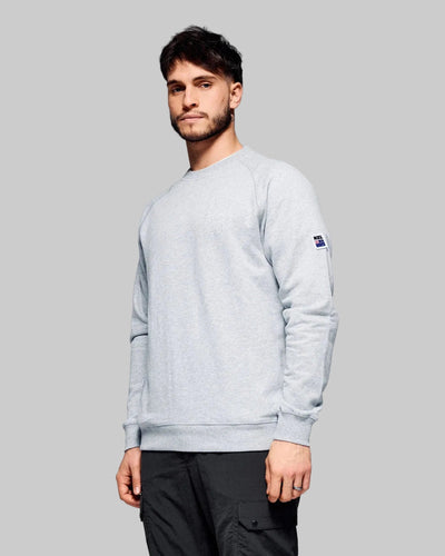 Man wearing a light gray sweatshirt with a brand logo on a gray background