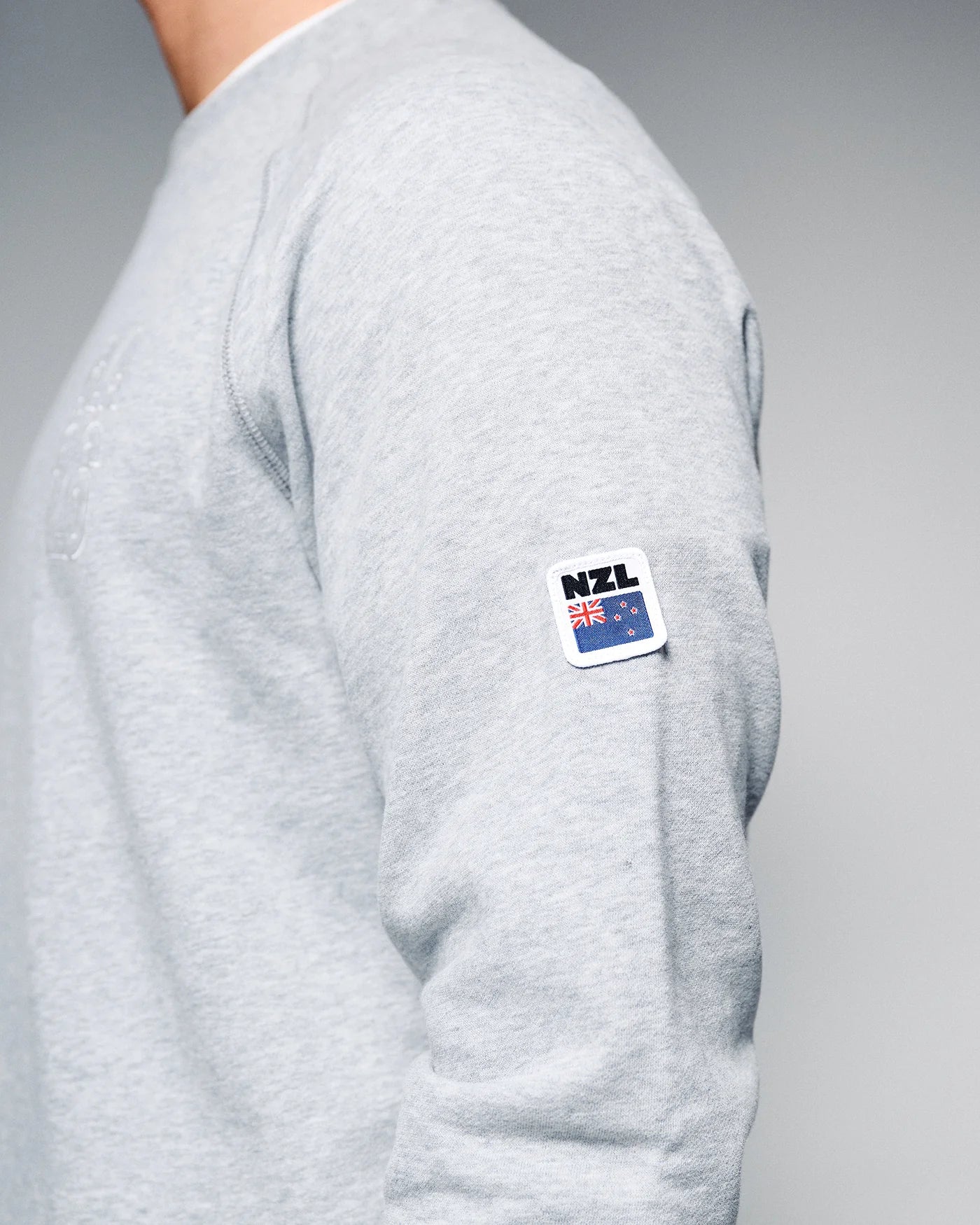 Gray sweatshirt with a NZL flag patch on a gray background