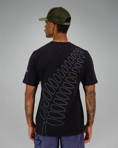Man wearing a black t-shirt with NZ Team Fern print covering the back in dark grey.