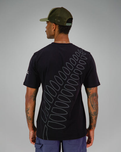 Man wearing a black t-shirt with NZ Team Fern print covering the back in dark grey.