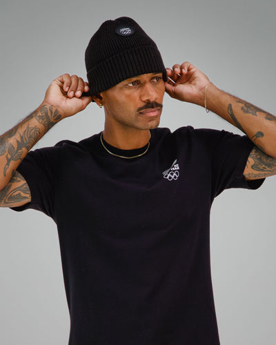 Man wearing a black t-shirt with NZ Team logo on front left side