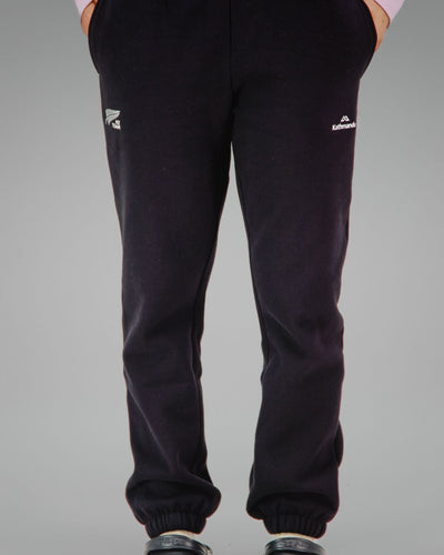 Person wearing black sweatpants with NZ team logo on the right front pocket