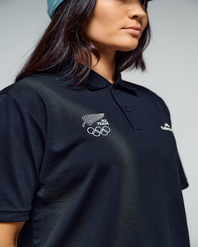Person wearing a black polo shirt with NZ team logo